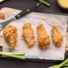 top view fried chicken wings cutting board with green onions fork